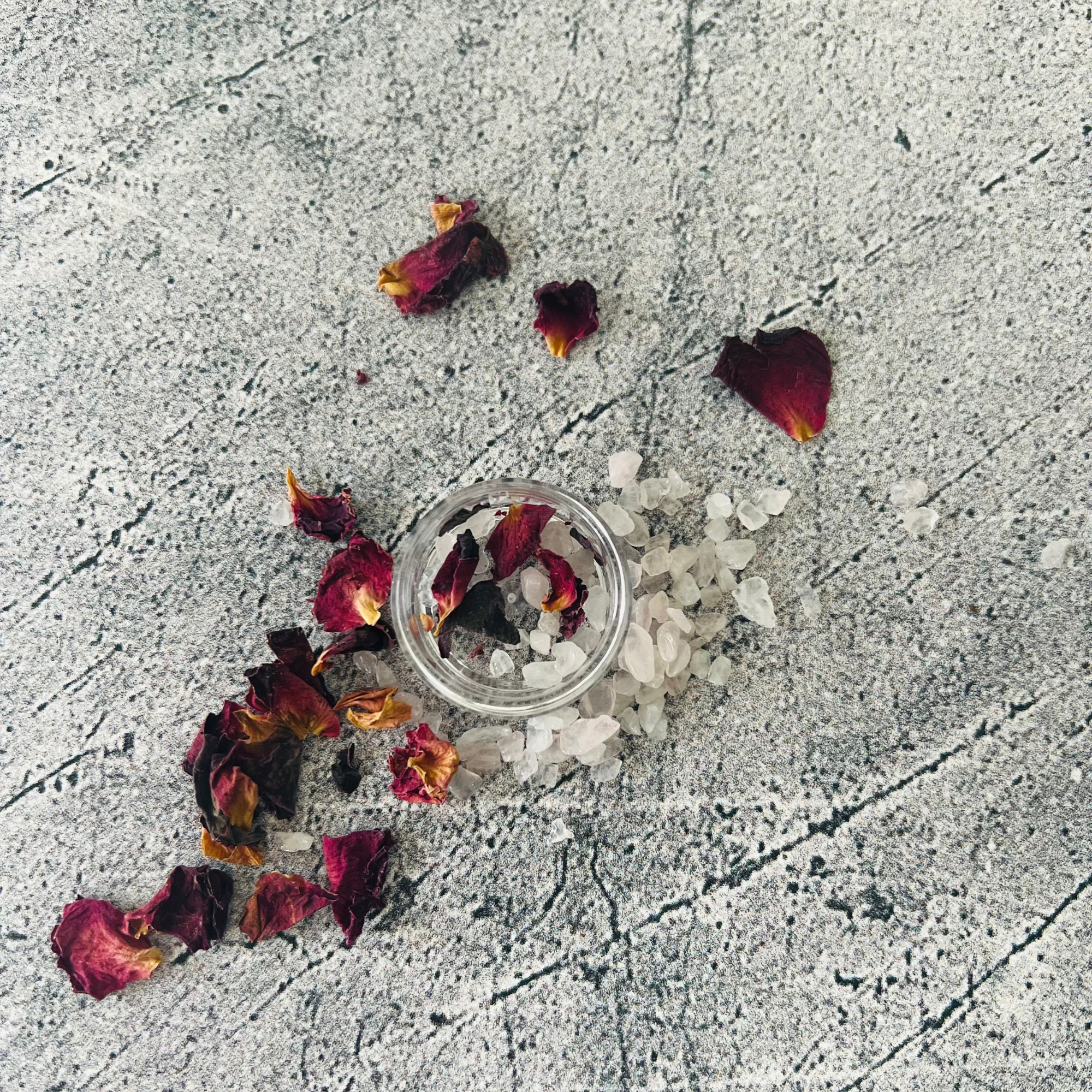 rose petals and rose quartz crystals on a gray tabletop