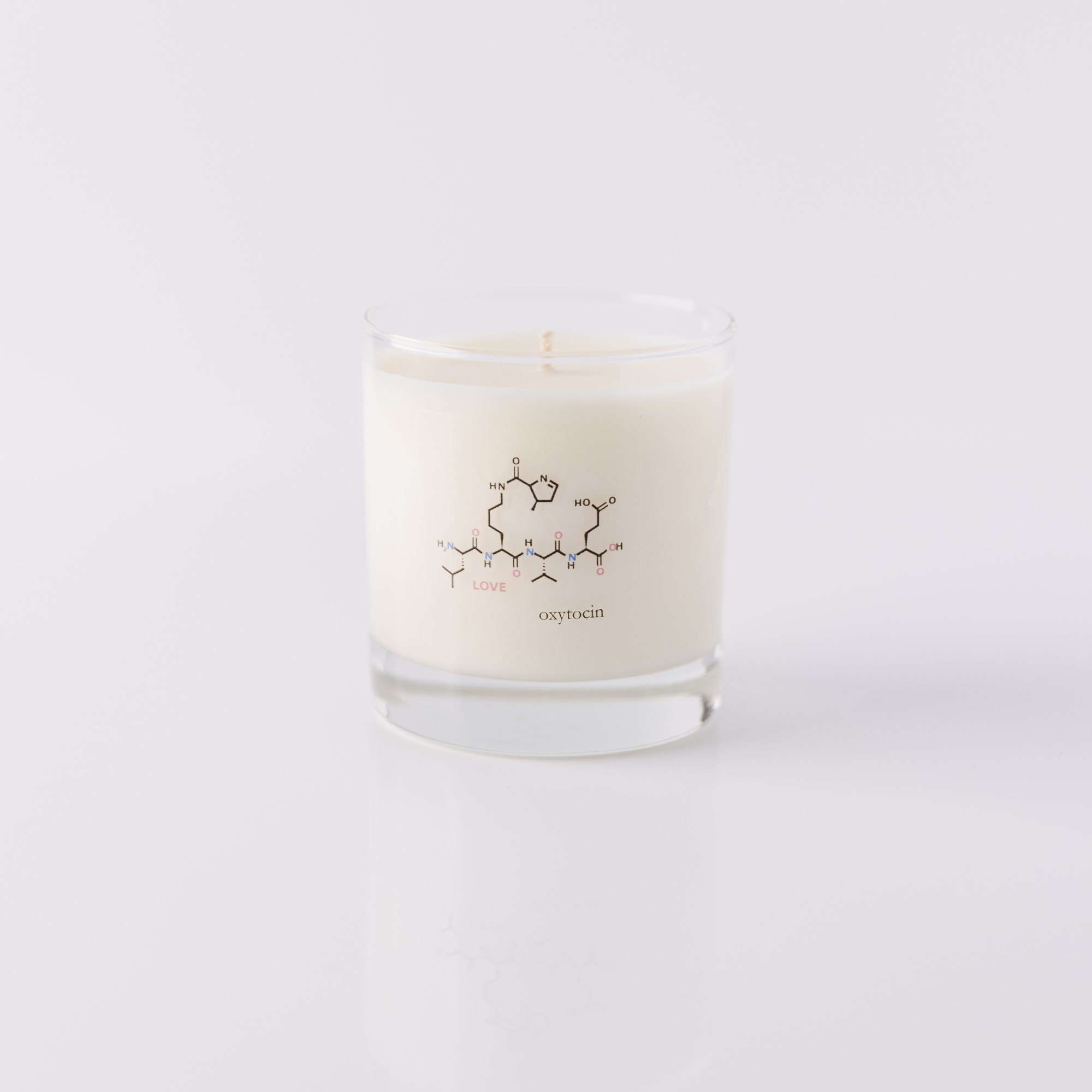 clear glass jar candle with the oxytocin molecule says oxytocin and love on an all white background