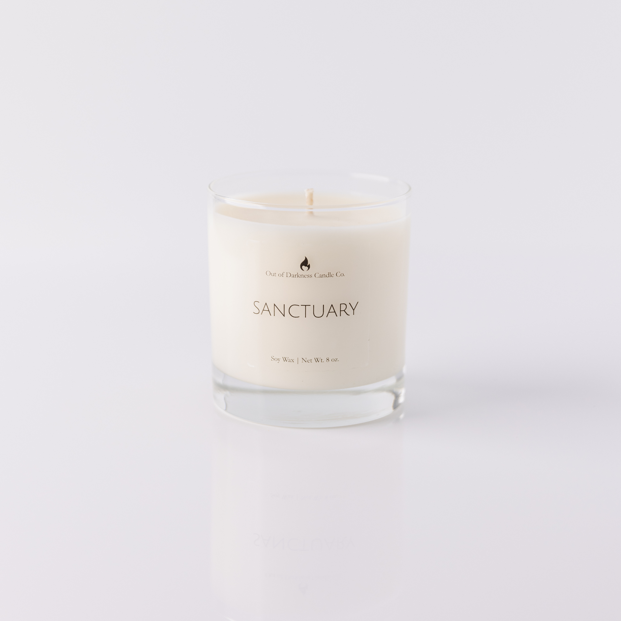 Clear glass candle jar says sanctuary all white background