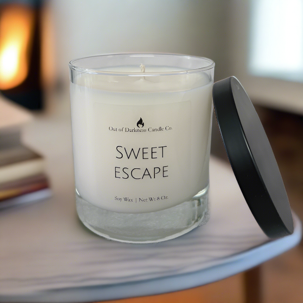clear glass jar candle says sweet escape with black metal lid resting on candle 